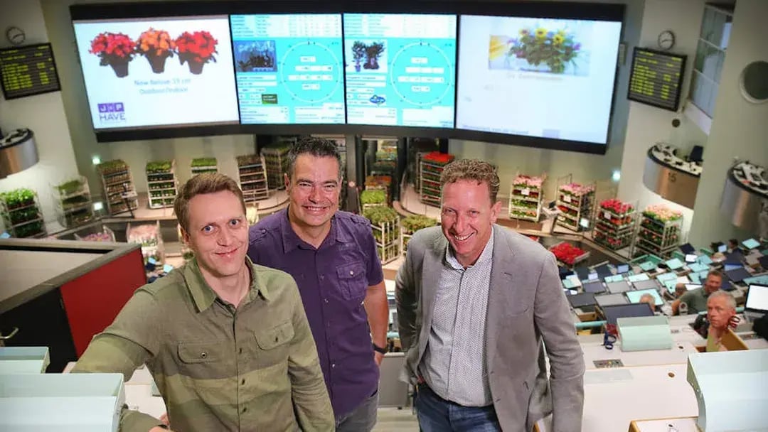 Drie mannen poseren in de bloemenveiling van Aalsmeer.