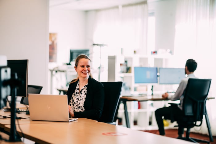 Een vrouw die lachend achter haar laptop zit