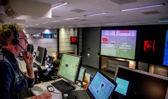 Man with a headphone watching data on several screens