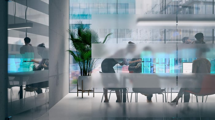 Collega's in een vergaderruimte kijken en wijzen naar lichten van schermen.