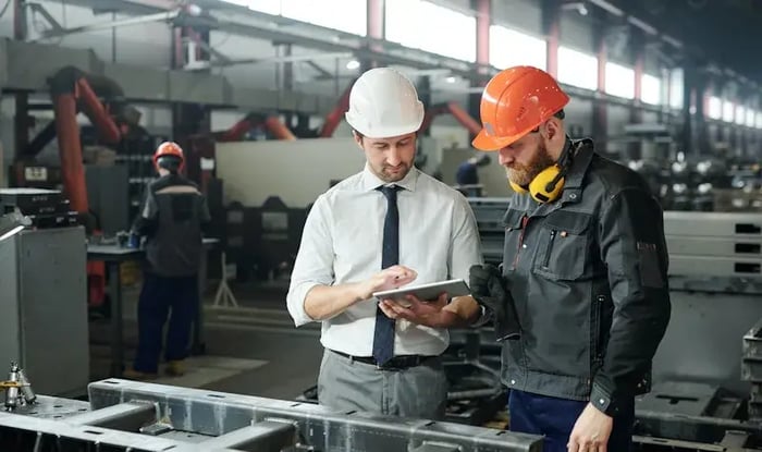 Twee mannen op een werkplaats met een tablet in de hand.