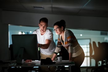 Een man en vrouw die bij een monitor staan