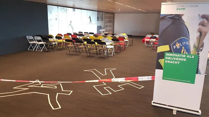 Lege zaal met stoelen, politietape en banner.