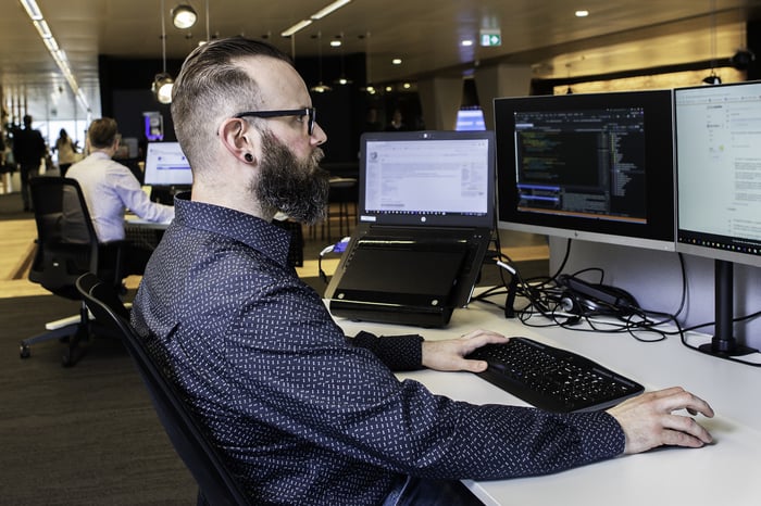 Een man aan het werk achter twee schermen