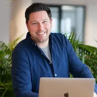 Lachende man staat achter laptop 