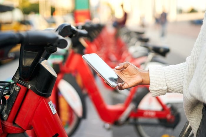 persoon houdt telefoon in hand met scooters op achtergrond