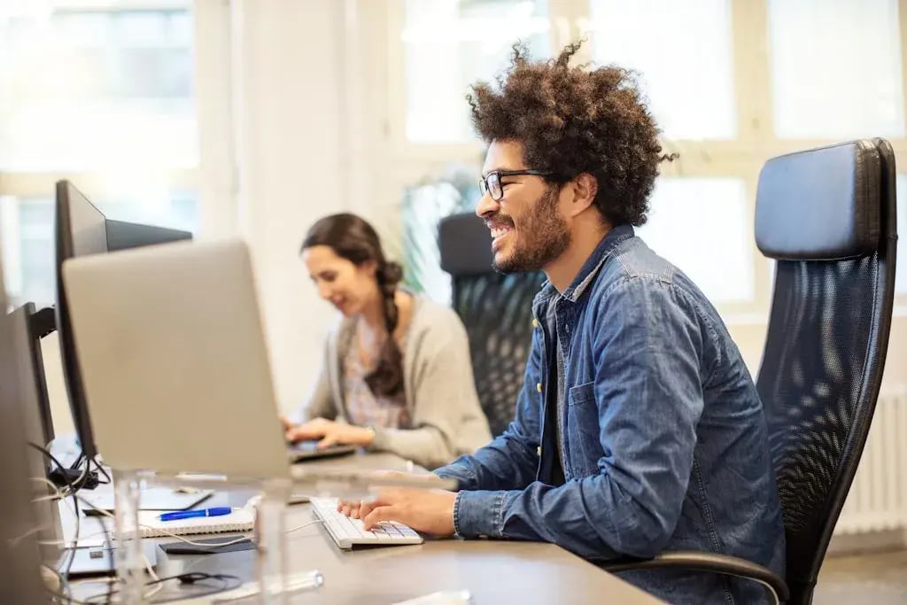 Twee collegas kijken lachend naar een scherm