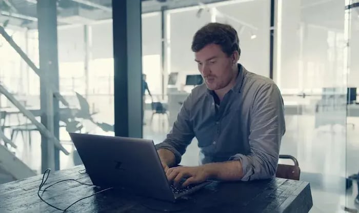 Man typt op kantoor op een laptop