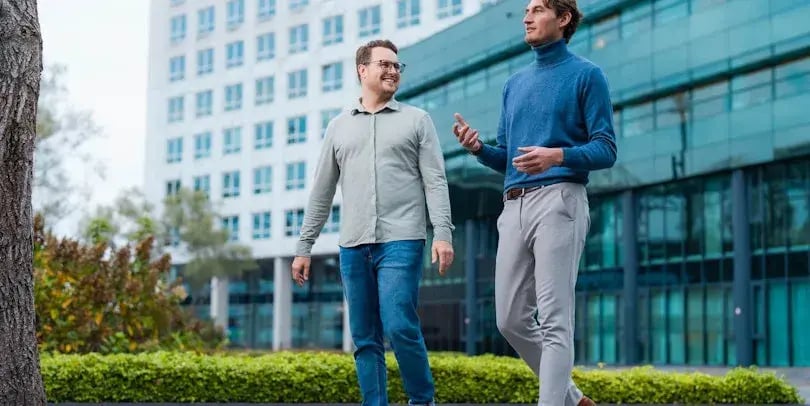 Two men are walking outside, talking to each other.
