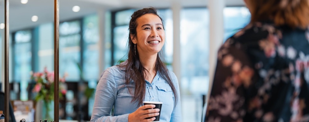 Vrouw lacht naar collega tegenover haar.