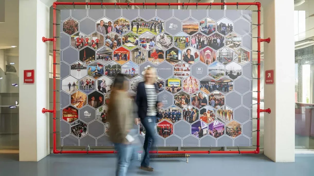 mannen lopen voorbij een scherm met allemaal afbeeldingen