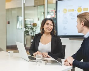 Man en vrouw overleggen met hun laptops open.