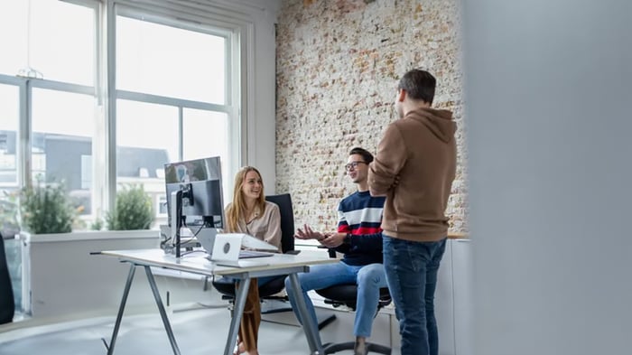 Colleagues are discussing something behind a desk.