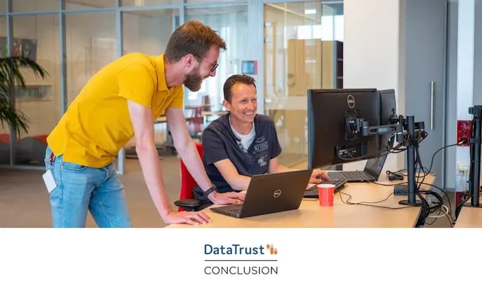 Twee collega's glimlachen en kijken naar een computerscherm