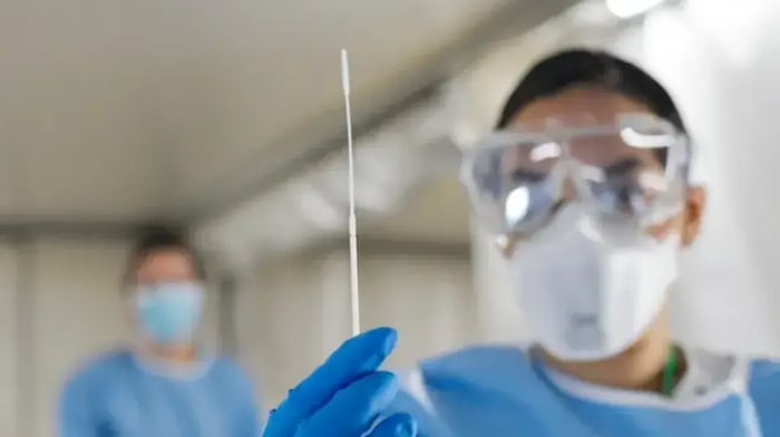 Vrouw in laboratorium met veiligheidsbril die naald ophoudt