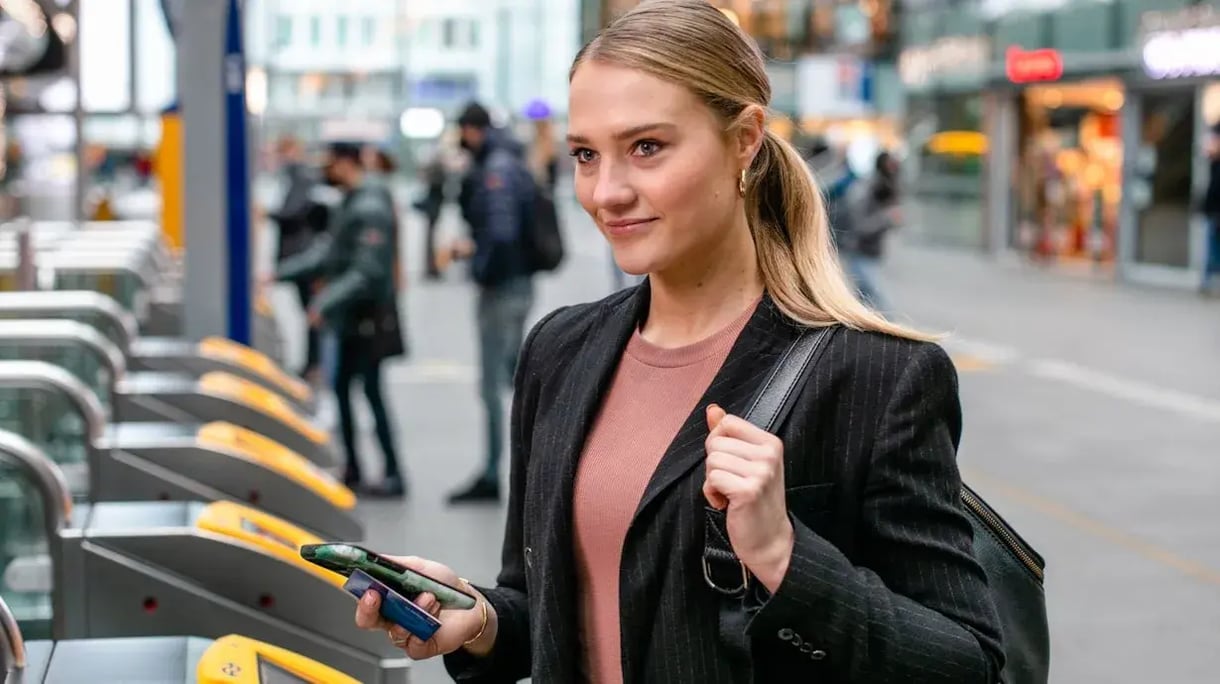 Woman with a blond ponytail in front of the check in of NS a train station