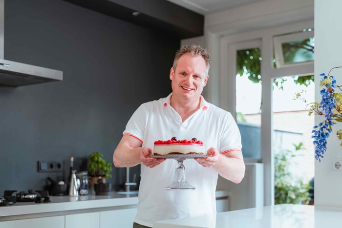 Man met een frambozentaart in zijn hand.