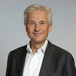 Portrait of Engbert Verkoren, a man with gray hair in a white shirt with a black coat smiling