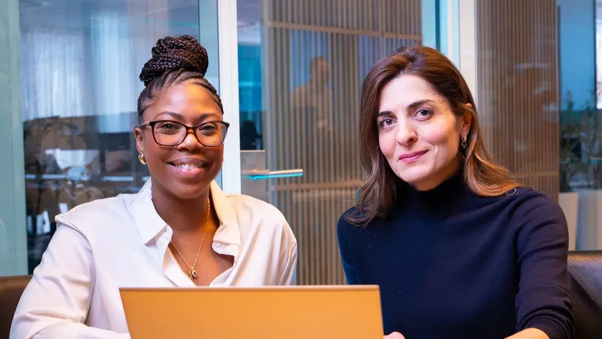 Twee lachende vrouwen achter een laptop