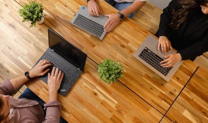 Drie collega's aan hun laptop aan tafel.