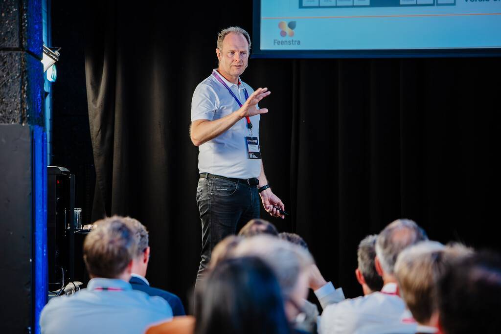 Presenter explains something to an audience in a meeting room.