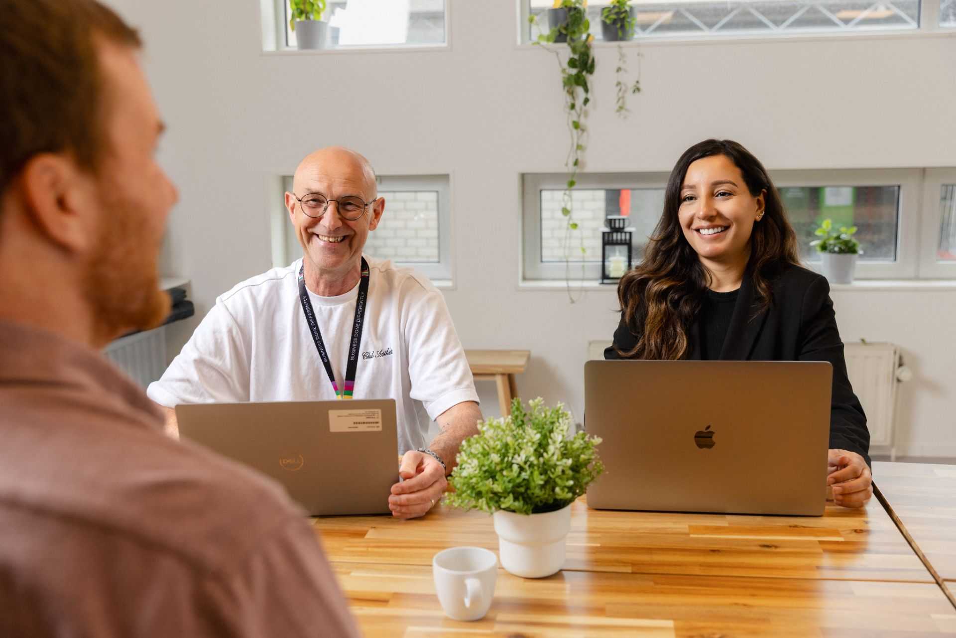 Twee collega's werken samen aan een computer en lachen.