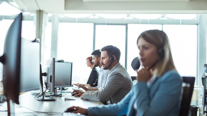 Collegas met een koptelefoon werken achten hun computers