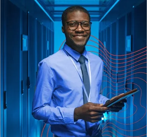 A darkskin man with glasses, smiling in front of the camera, in blue shirt with tie and a tablet in his hands