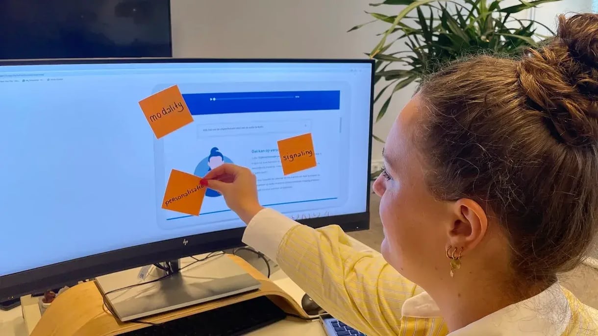 Een dame plakt sticky notes op haar scherm