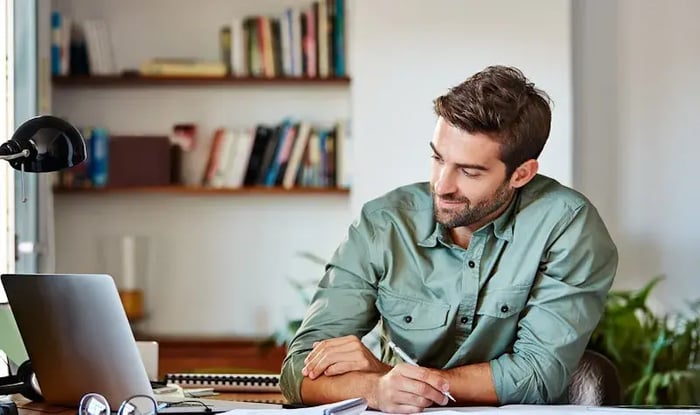 Man maakt notes met zijn laptop