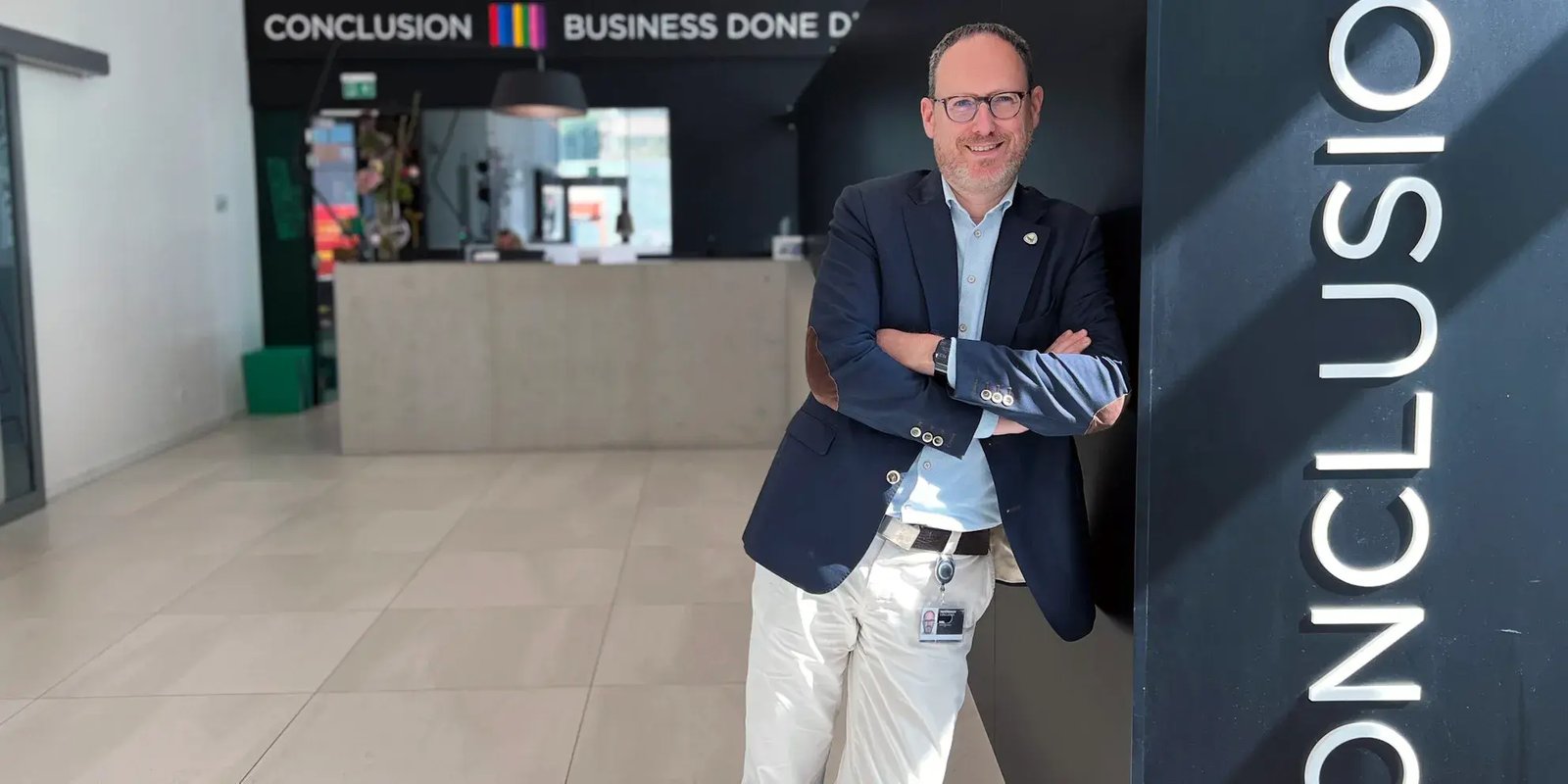 Roel Gloudemans in nette kleding leunt tegen een muur met daarop de tekst 'Conclusion'