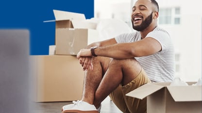 man die tussen verhuizendozen op de grond zit