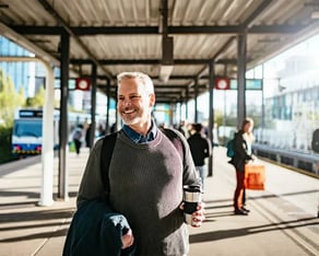 Lachende man op het perron wachten op het openbaar vervoer