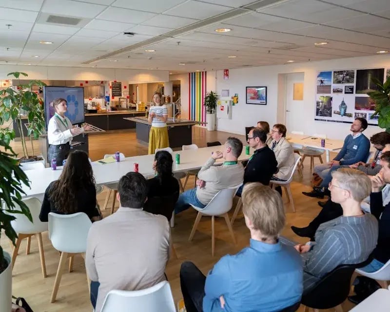 Publiek kijkt naar twee dames die in informele setting presenteren