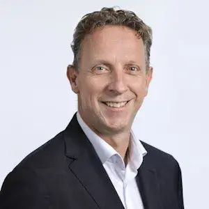 Lachende man in pak kijkt in de camera