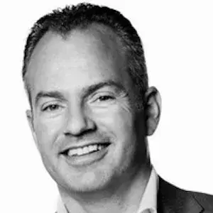 Lachende man met pak kijkt in de camera