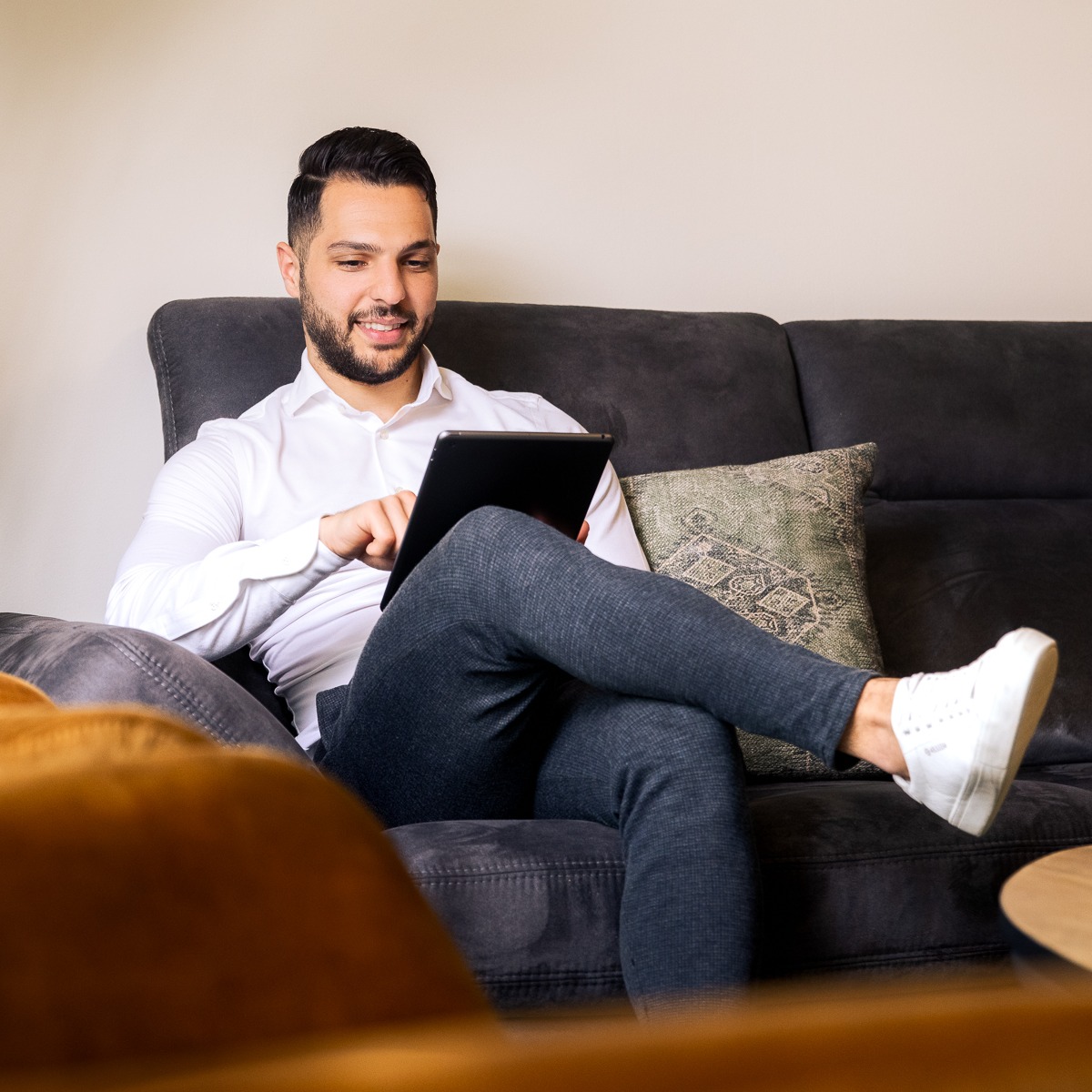 Man zit op zijn tablet op de bank.