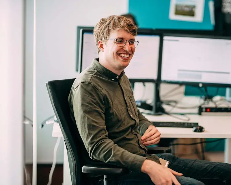 Een lachende man op een bureaustoel