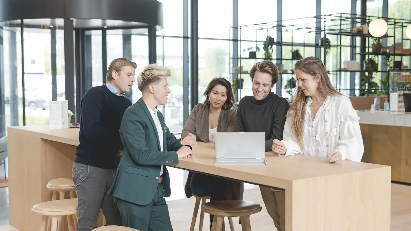 Groep collega's hangen rondom een laptop in de vergaderruimte