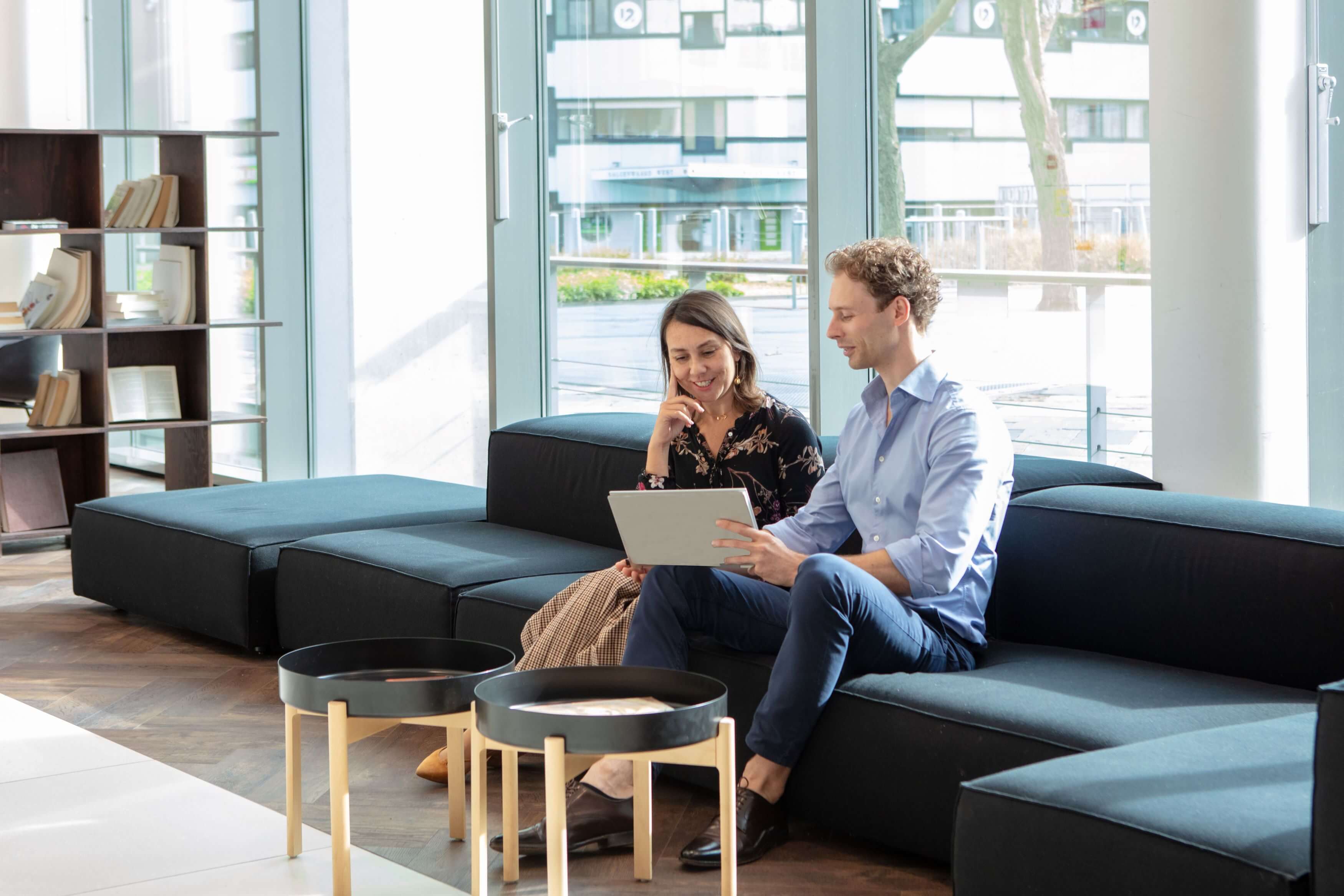 Two colleagues on the coach with a laptop.