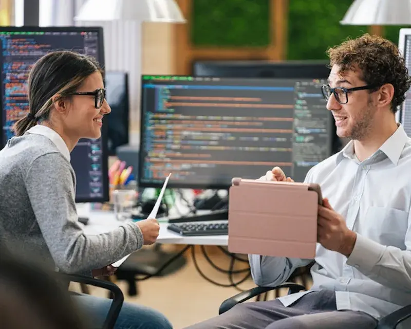 Twee collega's bespreken data gegevens op tablet en beeldscherm