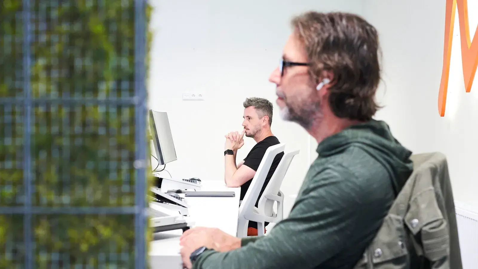 Two male colleagues are sitting behind their desks and concentrating on their screens.