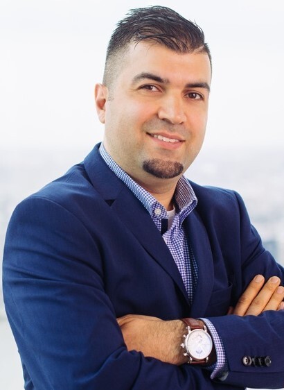 Een man met zijn armen over elkaar die glimlachend in de camera kijkt