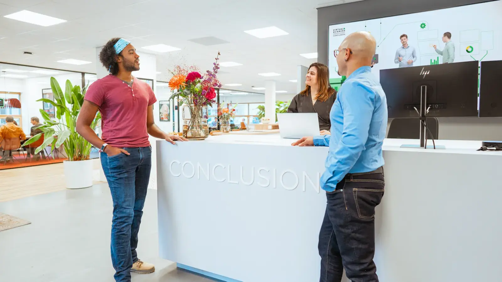 Twee mannen die kletsen met dame aan de balie