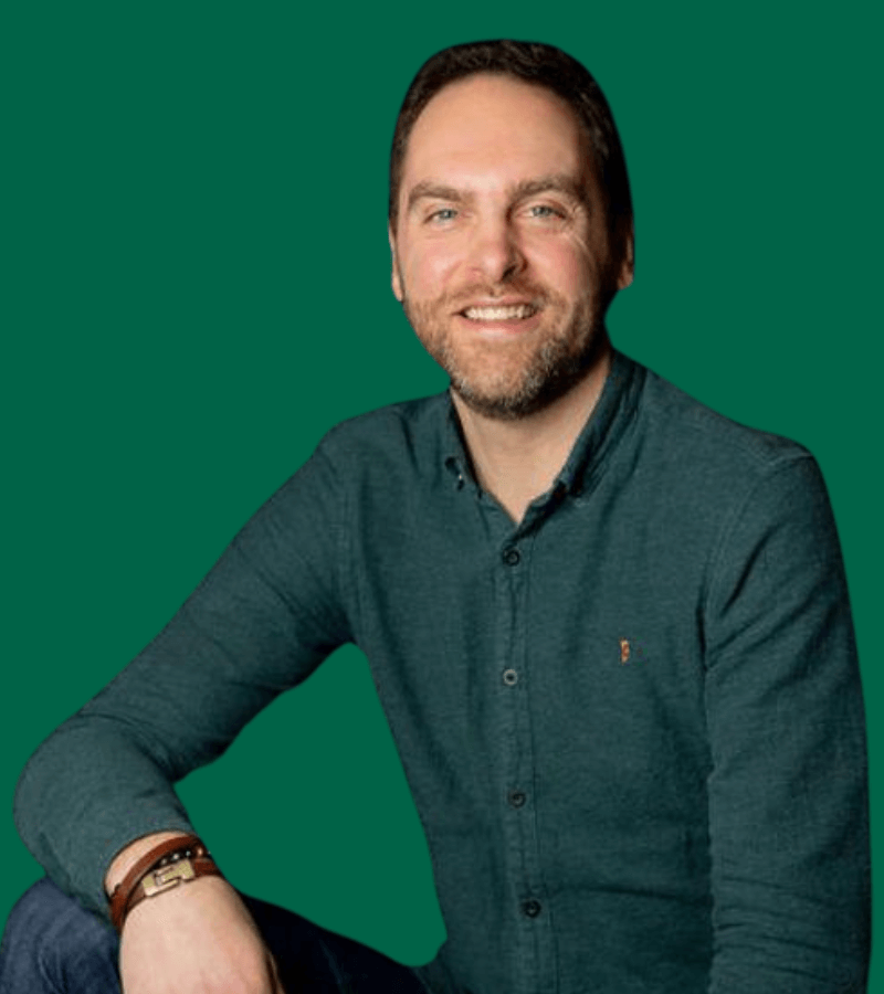 Mannelijke collega kijkt casual en vriendelijk.