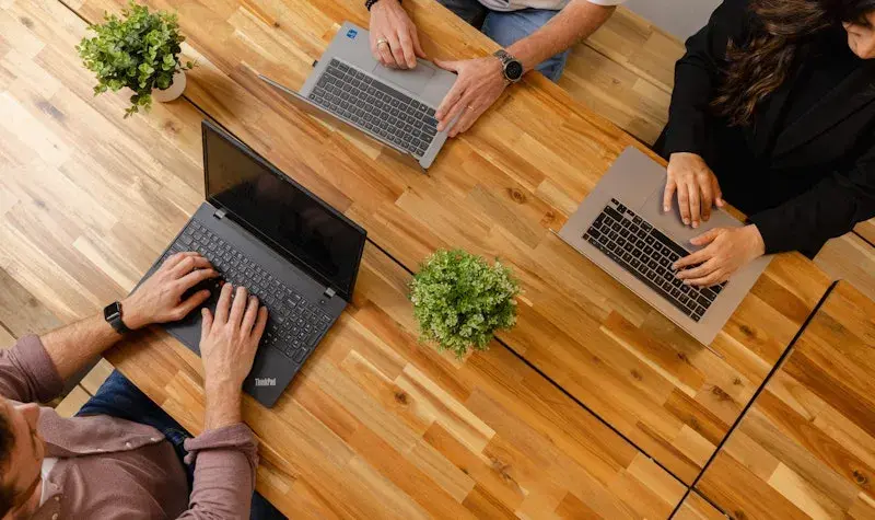 Drie collega's aan het werk met hun laptop.