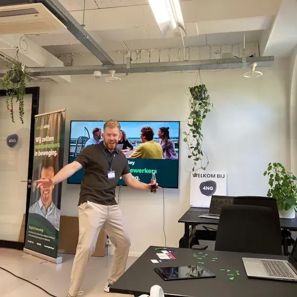 Een man staat vrolijk voor een tv scherm