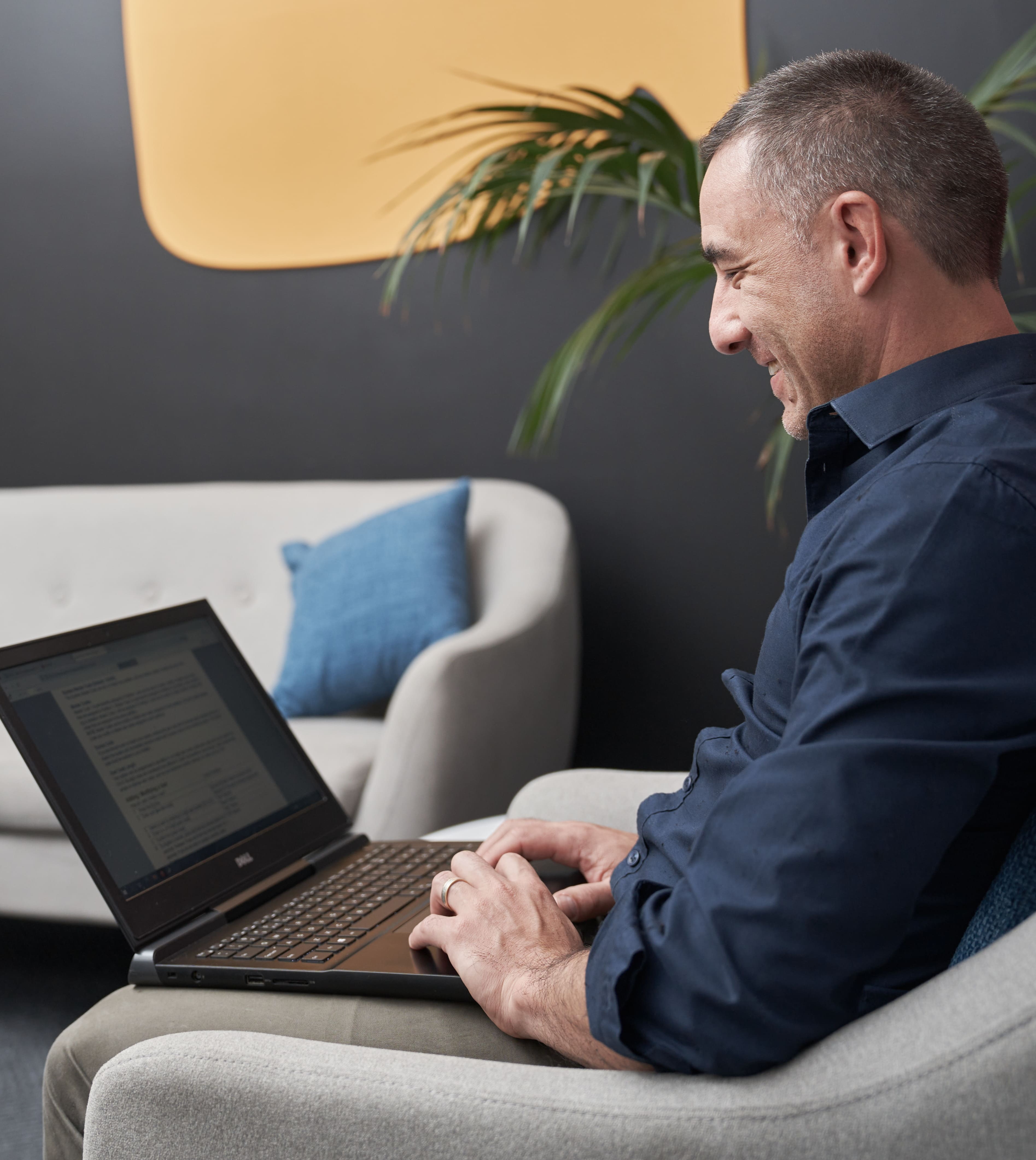 Man die op een bank zit en op zijn laptop bezig is (1)