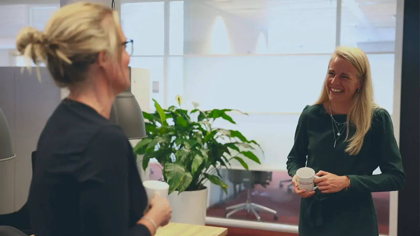 Twee collegas kijken vrolijk naar elkaar