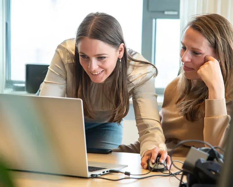 Twee dames werken vrolijk op een laptop